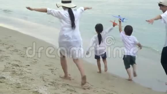快乐的亚洲家庭在度假的时候在海滩上坐一架飞机用伸直的手臂享受快乐和快乐视频的预览图