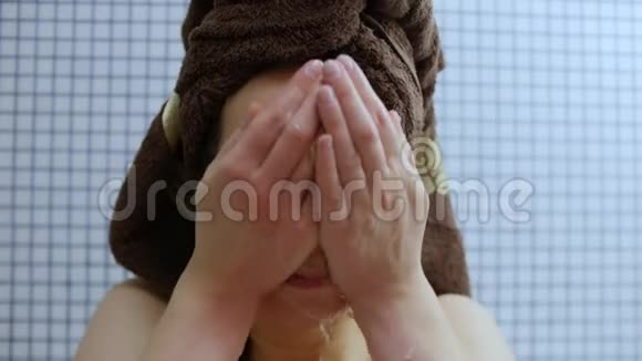 一个漂亮的年轻女子的特写在浴室里洗脸视频的预览图