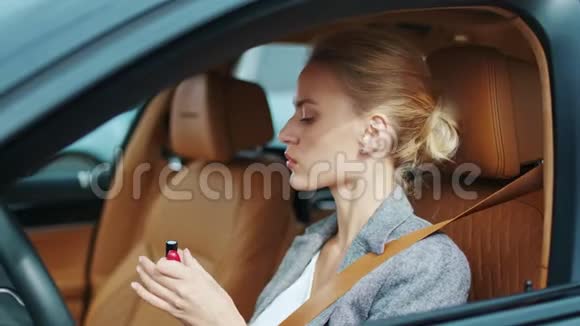 在车里涂红色口红的特写女人坐在豪华车里的性感女人视频的预览图