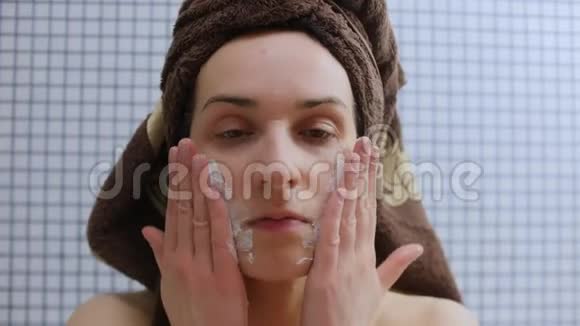 美丽的年轻女人用浴巾涂抹奶油视频的预览图