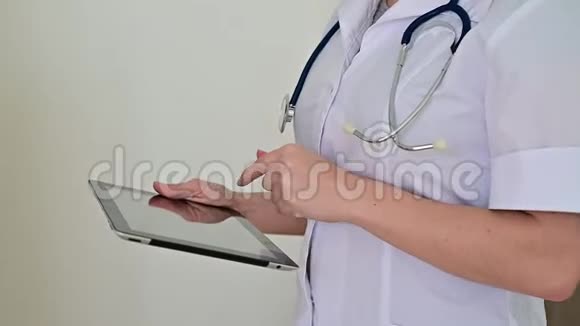 无法辨认的女医生制服使用平板电脑医务工作者在设备上接触病人弯着腰视频的预览图