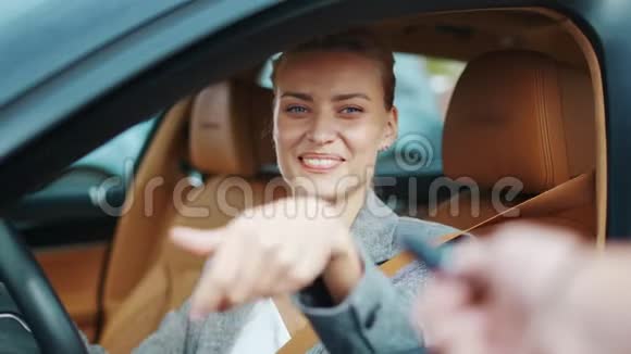 特写微笑的女人坐在新车里快乐的女人从新车里拿钥匙视频的预览图