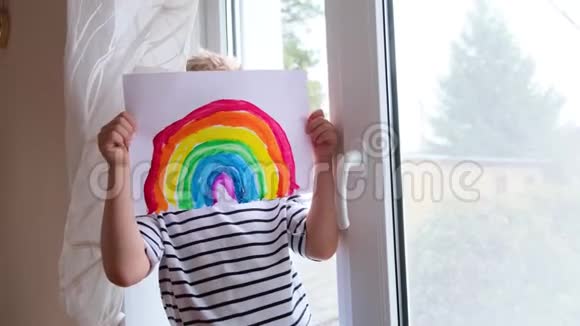 4k在Covid19号隔离期间一个小金发男孩在家里躲在彩虹图案后面玩得很开心让一切都好视频的预览图
