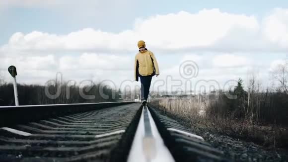 那个男孩在铁轨上行走从铁轨上直接看到美丽的景色冷静的镜头视频的预览图