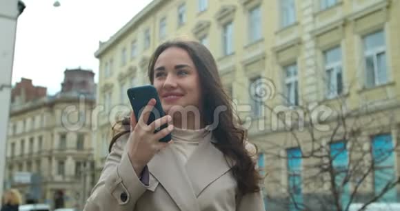 女士使用智能手机语音记录功能在线在城市街道语音留言使用智能手机语音的女孩视频的预览图