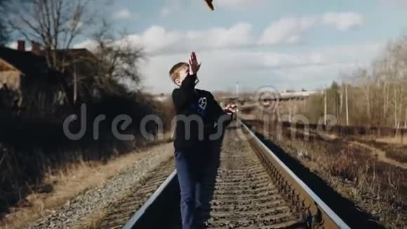 那个男孩沿着铁轨走把帽子扔上去抓住它视频的预览图