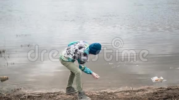 男孩把石头扔进水里使它们在水面上跳跃视频的预览图