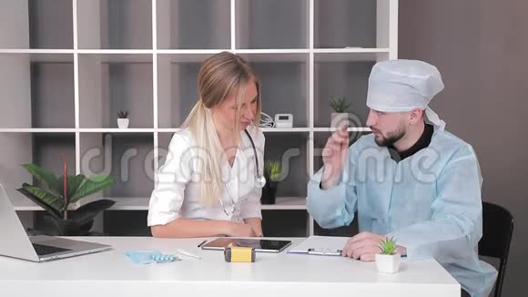 医生一男一女在办公室工作桌子上放着一块药片视频的预览图