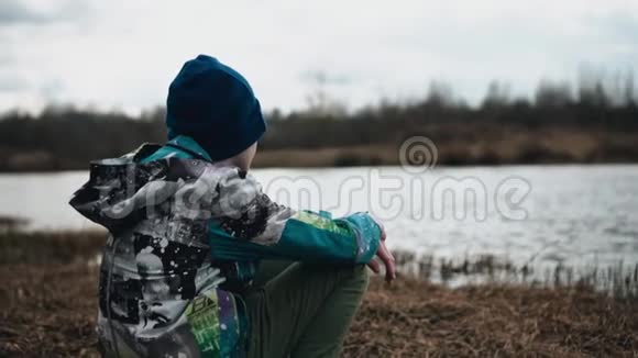 男孩坐在河岸上看着水很感性很感性视频的预览图