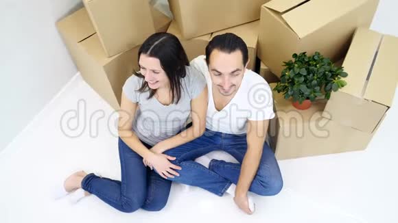 幸福的夫妻坐在新公寓的顶层靠近一叠纸板视频的预览图