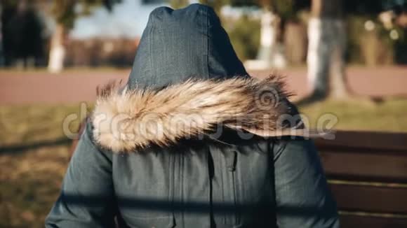 一个女孩坐在公园里头上戴着头巾风天气视频的预览图