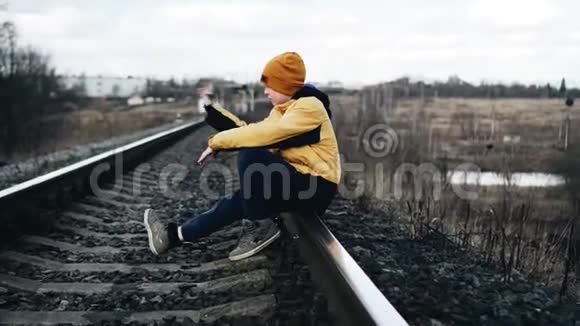 一个孤独的男孩坐在铁轨上把鹅卵石向前扔宁静气氛视频的预览图