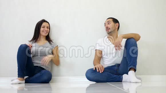 布鲁内特男女坐在白墙背景下举起双手表现出成长和成功视频的预览图