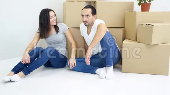 年轻的妻子和丈夫把沉重的大箱子搬到新的公寓里然后一起休息累了但筋疲力尽视频的预览图