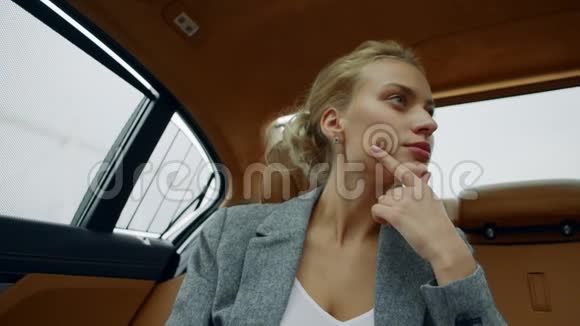 专注的女人坐在车上的肖像双足女孩在车后座思考视频的预览图