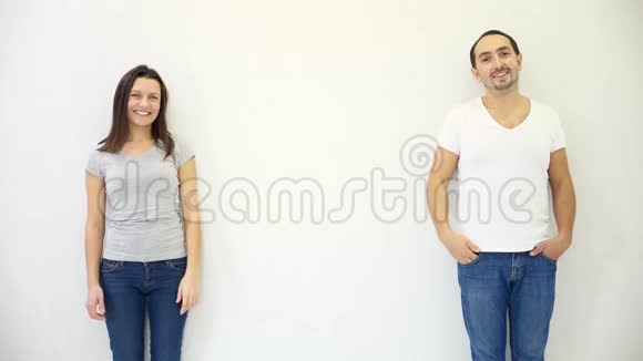 Brunette的男人和女人站在白色的墙壁背景下放下手表现出失落和失落视频的预览图