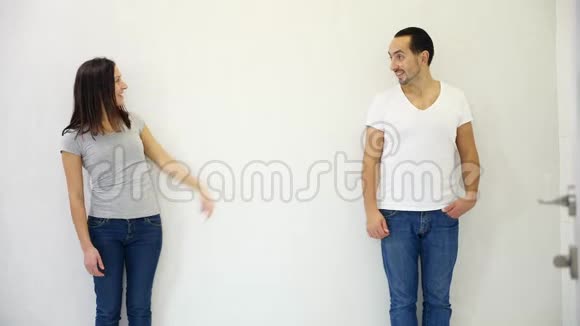 漂亮的男人和女人站在白色背景的不同侧面指向他们之间的共空间视频的预览图