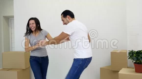 第一次买房的夫妇在客厅里和一堆盒子一起跳舞一起欢笑一起享受乐趣视频的预览图