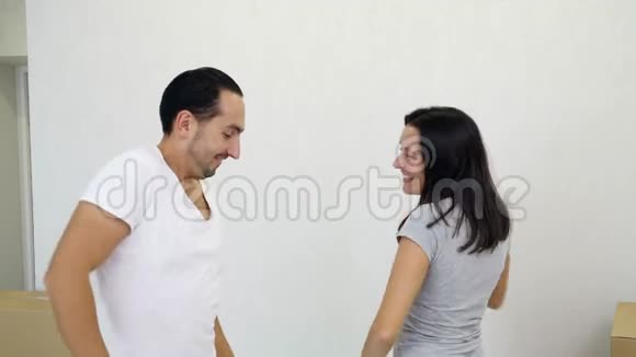 可爱的年轻家庭夫妇在他们舒适的新公寓里的纸板箱里玩得开心跳舞视频的预览图