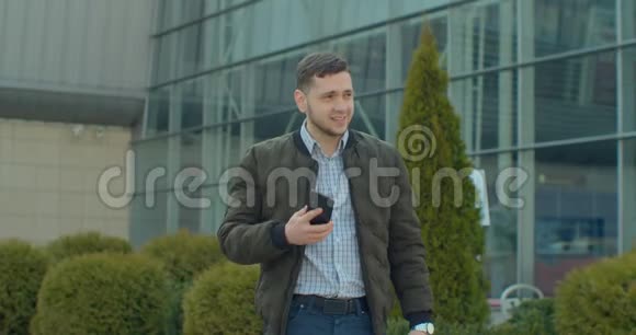 有魅力的男人正在兴致勃勃地打电话他正走在现代办公中心附近他在用视频的预览图