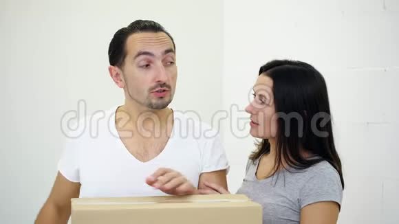 热情的年轻夫妇站在一间新公寓的纸板箱旁讨论房子的布局视频的预览图