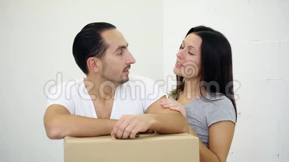 热情的年轻夫妇站在一间新公寓的纸板箱旁讨论房子的布局视频的预览图