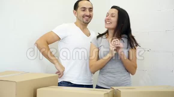 托西高加索夫妇从纸箱后面出现把他们新公寓的钥匙展示给相机视频的预览图