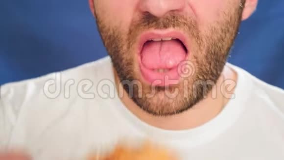特写一个男人在吃快餐咬一块鸡肉手里拿着金块健康饮食的问题视频的预览图