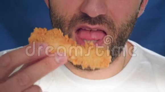 特写一个男人在吃快餐咬一块鸡肉手里拿着金块健康饮食的问题视频的预览图