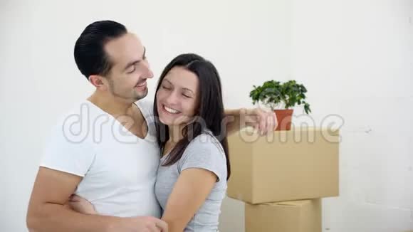 兴高采烈的丈夫情绪化地拥抱他的妻子因为他们是新房子的主人并显示了相机的钥匙视频的预览图