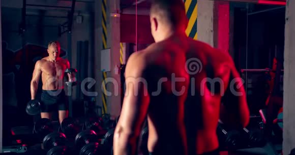 运动员人在镜子前举起哑铃锻炼锤在健身房辛勤工作的史诗灯视频的预览图