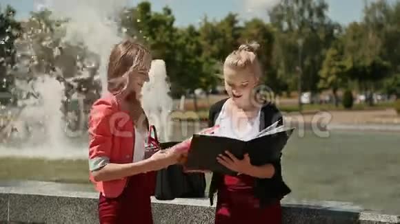 学院的年轻女学生一起在喷泉附近的公园里阳光灿烂视频的预览图
