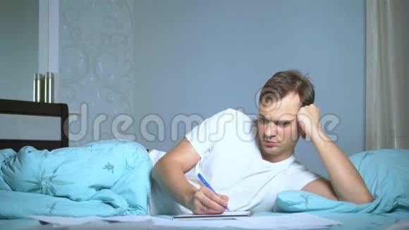 一个男人躺在床上写文件在家工作视频的预览图