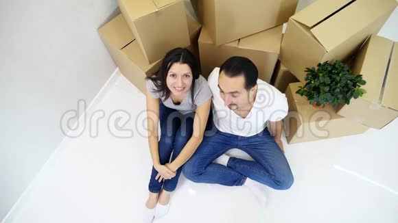 幸福的夫妻坐在新公寓的顶层靠近一叠纸板视频的预览图
