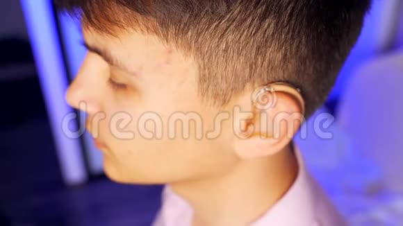 一个年轻人从他的耳朵上取出一个带有个人耳机的数字助听器耳聋视频的预览图