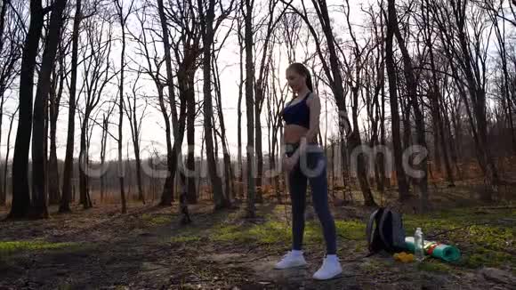 年轻苗条的女人在春天森林公园做健身运动运动和健康的生活方式视频的预览图