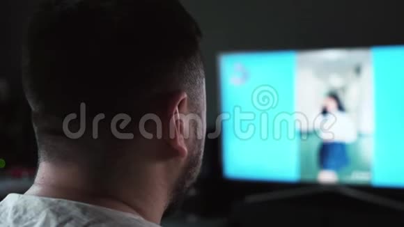 一个长胡子的白人男子在家里看电视屏幕上的狱卒录像视频的预览图