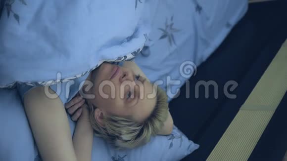 垂直的失眠的女人躺在黑暗的床上视频的预览图