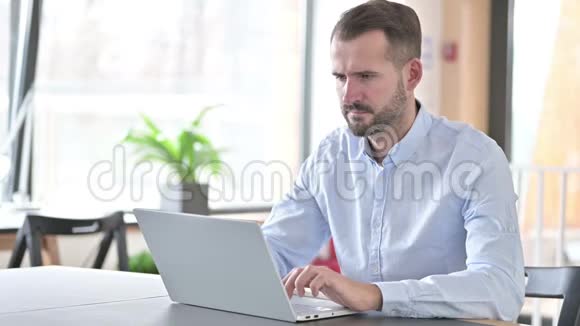 手提电脑的青年男子在办公室有头痛视频的预览图