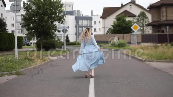 美丽的金发女人穿着裙子在路上跳舞视频的预览图