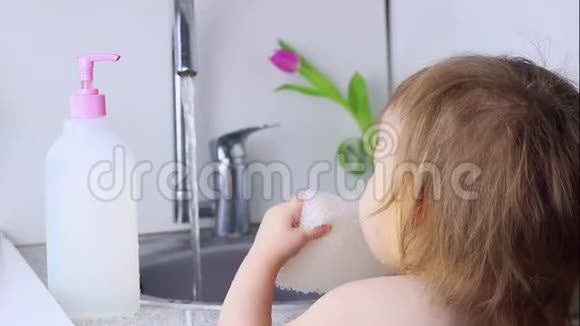 一个小婴儿要洗盘子从有机材料中取出一块安全的环保海绵把它拉出来视频的预览图