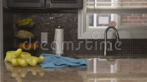 一个穿灰色T恤的年轻人在他家打扫厨房花岗岩台面他戴着一只亮黄色的橡胶手套视频的预览图