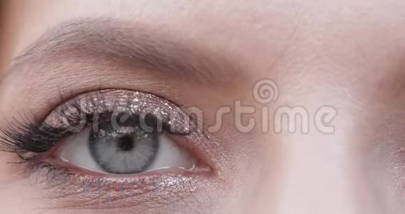 女人特写镜头灰绿色的雌性眼睛在镜头前闪烁视频的预览图