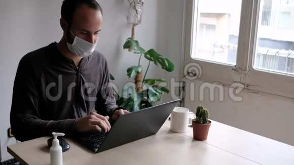 戴着医用口罩的年轻人在工作期间因冠状病毒爆发而在家咳嗽手提电脑及手机视频的预览图