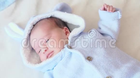特写新生婴儿全生长俯视图穿着米色背景蓝色衣服的新生儿穿蓝色上衣的婴儿视频的预览图