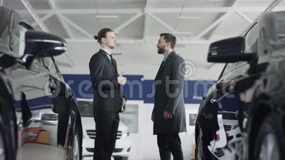 广拍业务员与男客户握手一位长胡子的男性客户在经销商处选择了汽车视频的预览图
