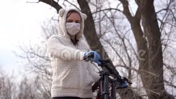 戴着医用口罩和手套的年轻女子骑着自行车站在农村手握舵保护妇女视频的预览图