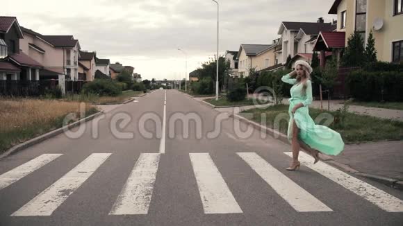 美丽的女人穿着薄荷长礼服戴着白帽子走在农村的街道上视频的预览图