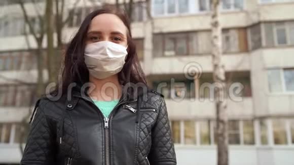 站在街上的年轻女子戴着医用面具的肖像成年女性用面具遮住她的脸视频的预览图