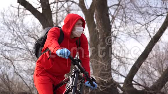 戴着医用口罩和手套的年轻人在乡下咳嗽穿红色西装保护自己免受疾病侵袭的成年男性视频的预览图